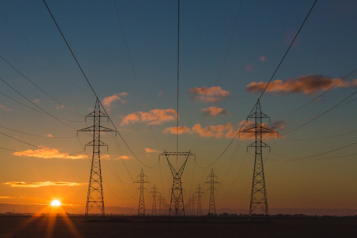 Power lines across an open field at sunset